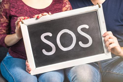 Couple holding "SOS" sign
